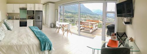 a bedroom with a bed and a kitchen and a balcony at Mount Bay in Hout Bay