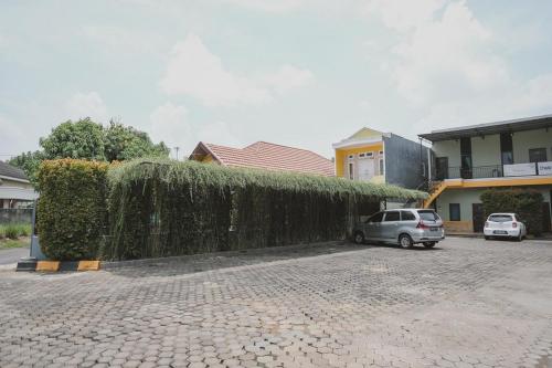 a car parked in a parking lot next to a hedge at RedDoorz Syariah near Kantor Walikota Jambi in Jambi