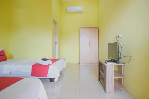 a bedroom with a bed and a tv in it at RedDoorz Syariah near Kantor Walikota Jambi in Jambi