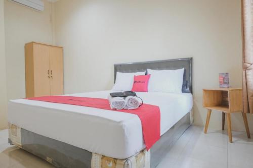 占碑市的住宿－RedDoorz Syariah near Kantor Walikota Jambi，卧室配有一张大白色床和红色毯子