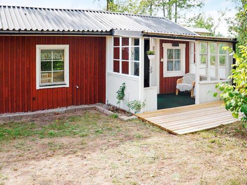 une maison rouge avec une terrasse en bois devant elle dans l'établissement 3 person holiday home in OSKARSHAMN, à Oskarshamn