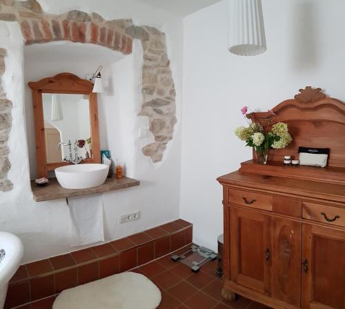 ein Badezimmer mit einem Waschbecken und einem Spiegel sowie einem Holzschrank in der Unterkunft Kleines Häuschen im Grünen in Monheim