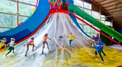 a group of children playing on an indoor water slide at Vakantiepark de Bergen in Wanroij