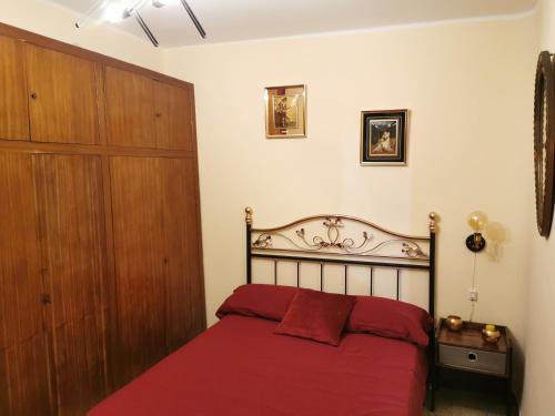 1 dormitorio con cama roja y armario de madera en Plaza, en Alagón