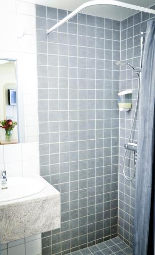 a blue tiled bathroom with a sink and a shower at Hasse på Sjökanten Hotell & Restaurang in Jönköping