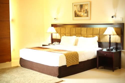 THE AVENUE HOTEL & SUITES في شيتاغونغ: غرفه فندقيه بسرير ومصباحين