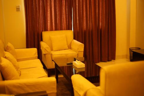 a living room with chairs and a chair and a table at The Avenue Hotel & Suites in Chittagong