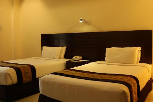 THE AVENUE HOTEL & SUITES في شيتاغونغ: غرفه فندقيه سريرين وتلفون