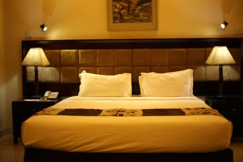 a hotel room with a large bed with two lamps at THE AVENUE HOTEL & SUITES in Chittagong