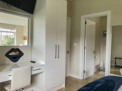 a bedroom with white cabinets and a bed and a mirror at Mount Bay in Hout Bay