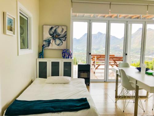 a bedroom with a bed and a desk and a table at Mount Bay in Hout Bay