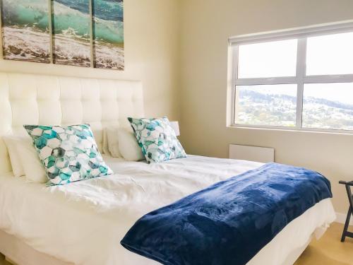 a bedroom with a white bed with pillows and a window at Mount Bay in Hout Bay