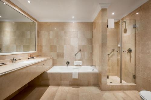 a bathroom with a tub and a shower and a sink at The Edward in Durban