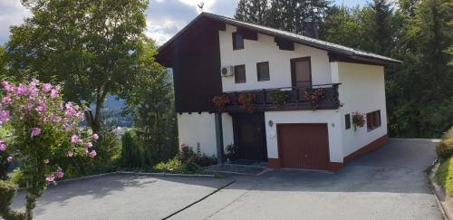 ein weißes Haus mit einem Balkon mit Blumen darauf in der Unterkunft Comfort and Views in Hermagor