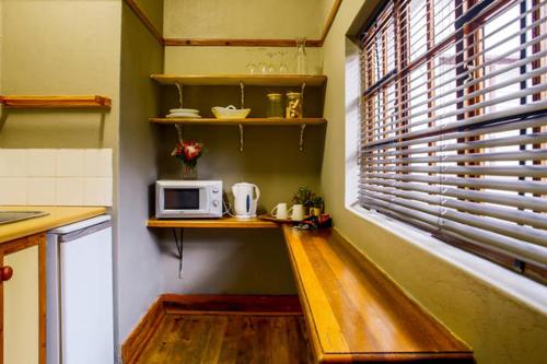 a kitchen with a counter and a microwave on a shelf at Nobis House in Bloemfontein