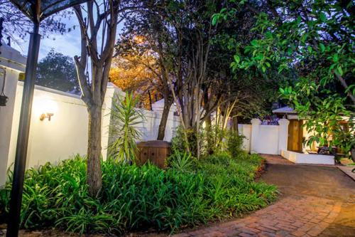 a house with a fence and trees and a brick driveway at Nobis House in Bloemfontein