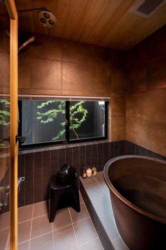 a bathroom with a large tub and a window at Tsumugi Horikawakichimonji in Kyoto