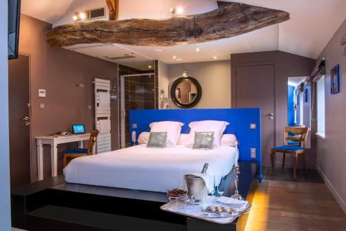 Schlafzimmer mit einem großen weißen Bett mit blauem Kopfteil in der Unterkunft Frédéric Carrion Hôtel et Spa in Viré