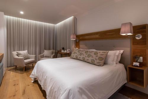 a bedroom with a large white bed and a chair at Oceans Guest House & Luxurious Apartments in Struisbaai