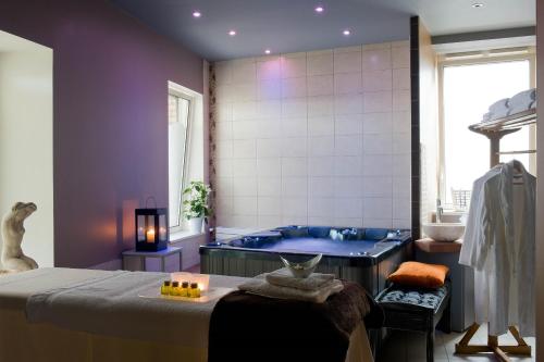 a bathroom with a tub and a bed in a room at Frédéric Carrion - Cuisine, Hôtel & Spa in Viré