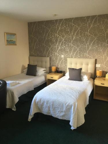 a hotel room with two beds and two tables at Deveron Lodge Guest House in Turriff