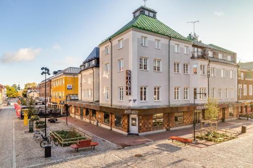 a large white building on a city street with benches at Ludvika Stadshotell in Ludvika