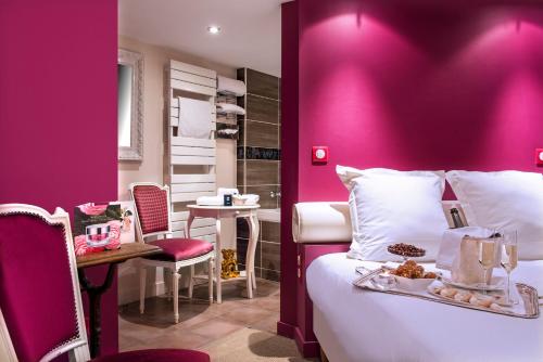 a pink room with a bed and a table and a tableablish at Frédéric Carrion - Cuisine, Hôtel & Spa in Viré