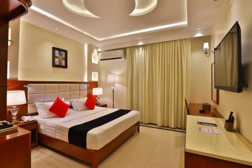 Schlafzimmer mit einem Bett mit roten Kissen und einem TV in der Unterkunft Dreams Houses furnished Suites in Tabuk