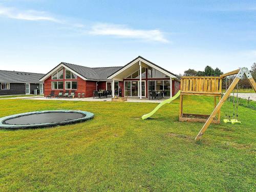 une maison avec une aire de jeux dans la cour dans l'établissement 18 person holiday home in Grenaa, à Grenå