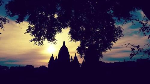 a silhouette of a building with the sunset in the background at Rumah Desa Homestay in Prambanan