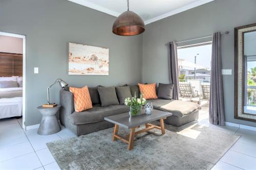 a living room with a couch and a table at 5 Options Guest House in Bloubergstrand