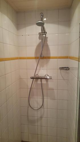 a shower with a hose in a white tiled bathroom at Botel Sailing Home in Amsterdam
