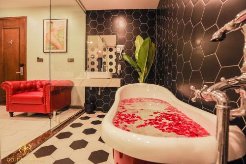 a bathroom with a sink and a red chair at Golden Hotel in Hanoi