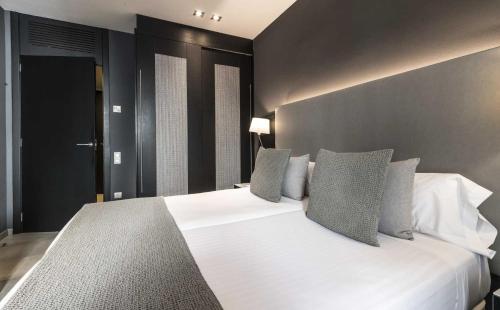 a bedroom with a large white bed with gray pillows at Hotel Actual in Barcelona