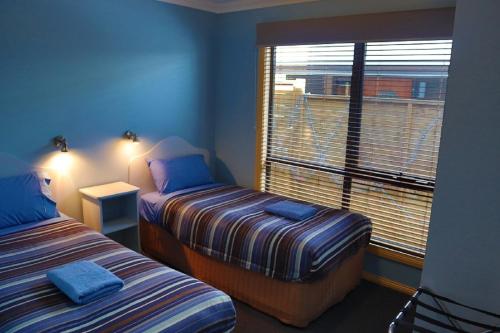 1 dormitorio con 2 camas y ventana grande en Strahan Bungalows, en Strahan