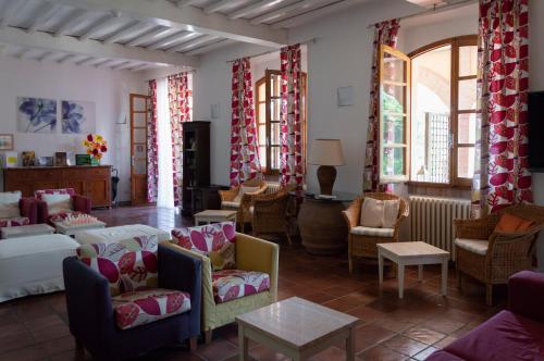 a living room with couches and chairs and windows at Hotel Le Renaie in San Gimignano