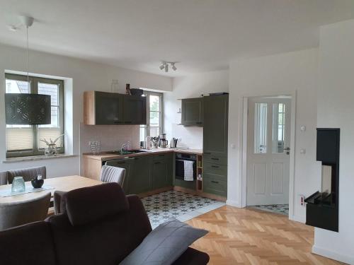 a kitchen with green cabinets and a table in a living room at Ferienhaus Schütt in Zempin