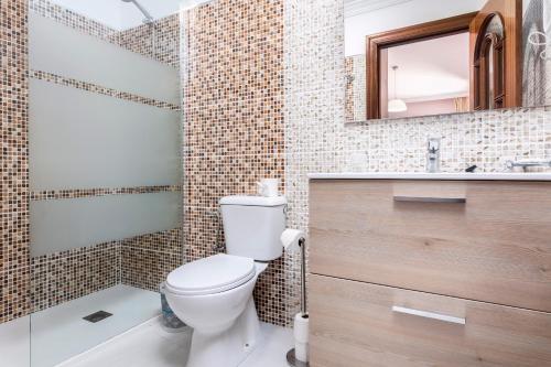 a bathroom with a toilet and a sink and a mirror at Villas El Paraiso in Morro del Jable