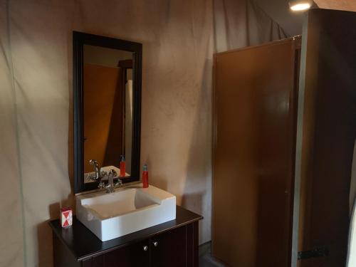 ein Bad mit einem Waschbecken und einem Spiegel in der Unterkunft Lorian safari camp limited in Narok