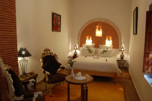 a bedroom with a bed and a table and a chair at Riad Les Trois Palmiers El Bacha in Marrakech