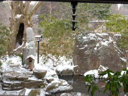 a statue in a garden in the snow at Yamabiko Ryokan in Minamioguni