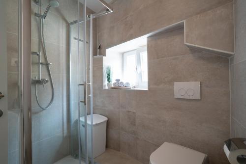 a bathroom with a shower and a toilet and a window at Apartment Lassy by Irundo in Rovinj
