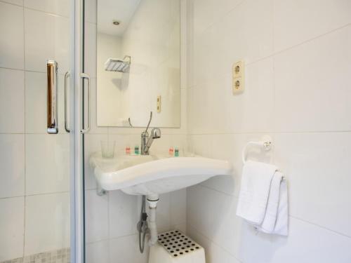 y baño blanco con lavabo y ducha. en Hostal Felipe V, en Madrid