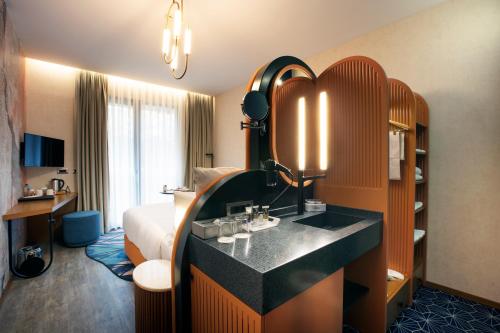 a hotel room with a bed and a vanity with a mirror at Mercure Istanbul Bakirkoy in Istanbul