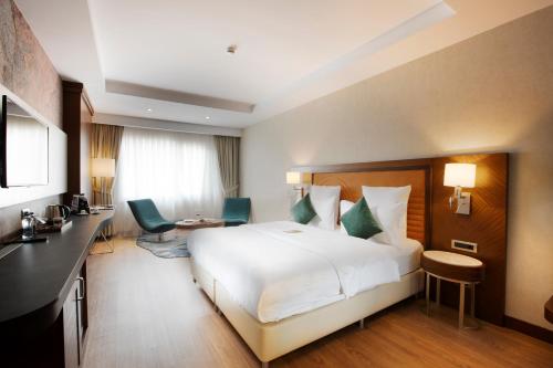 a hotel room with a white bed and a desk at Mercure Istanbul Bakirkoy in Istanbul