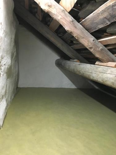 an attic room with wooden stairs and a green floor at Rustico Ca d'Damunt in Cevio