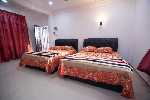 2 letti posti uno accanto all'altro in una stanza di Wan Danisha Villa Inn a Kota Bharu