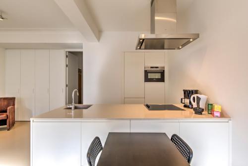 a kitchen with white cabinets and a table and chairs at The Meir Lodge. Apartments in heart of Antwerp in Antwerp