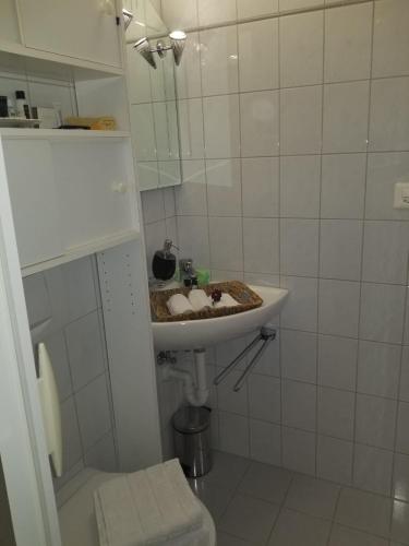 a white bathroom with a sink and a mirror at Studio direkt am Bodensee in Thal