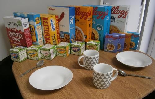 due piatti e due tazze su un tavolo con scatole di cereali di The Barn - Ilkeston - 1 Bedroom Flat, 2 Beds, Close to M1-A52 Long Eaton - Nottingham - Derby - Derbyshire - 400Mbs WiFi Free Parking! a Ilkeston